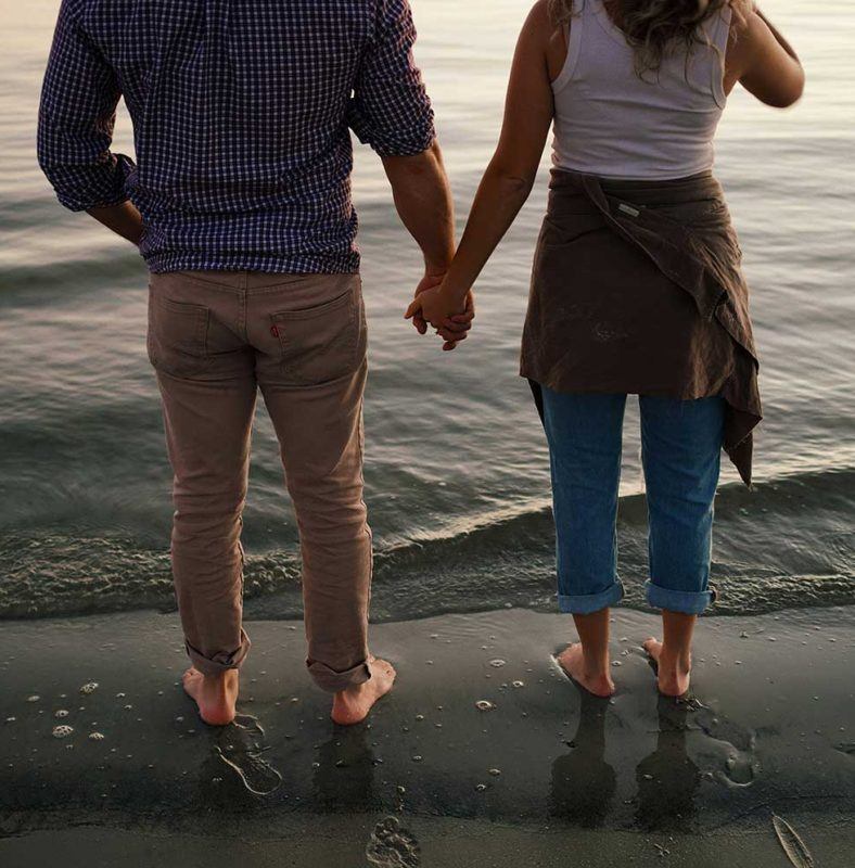 a man and a woman holding hands on the beach