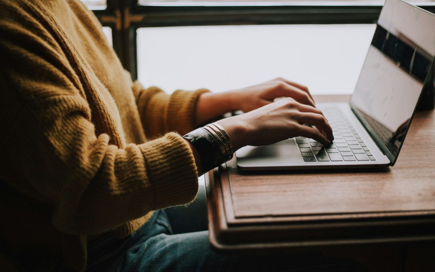 a person using a laptop on a wooden desk