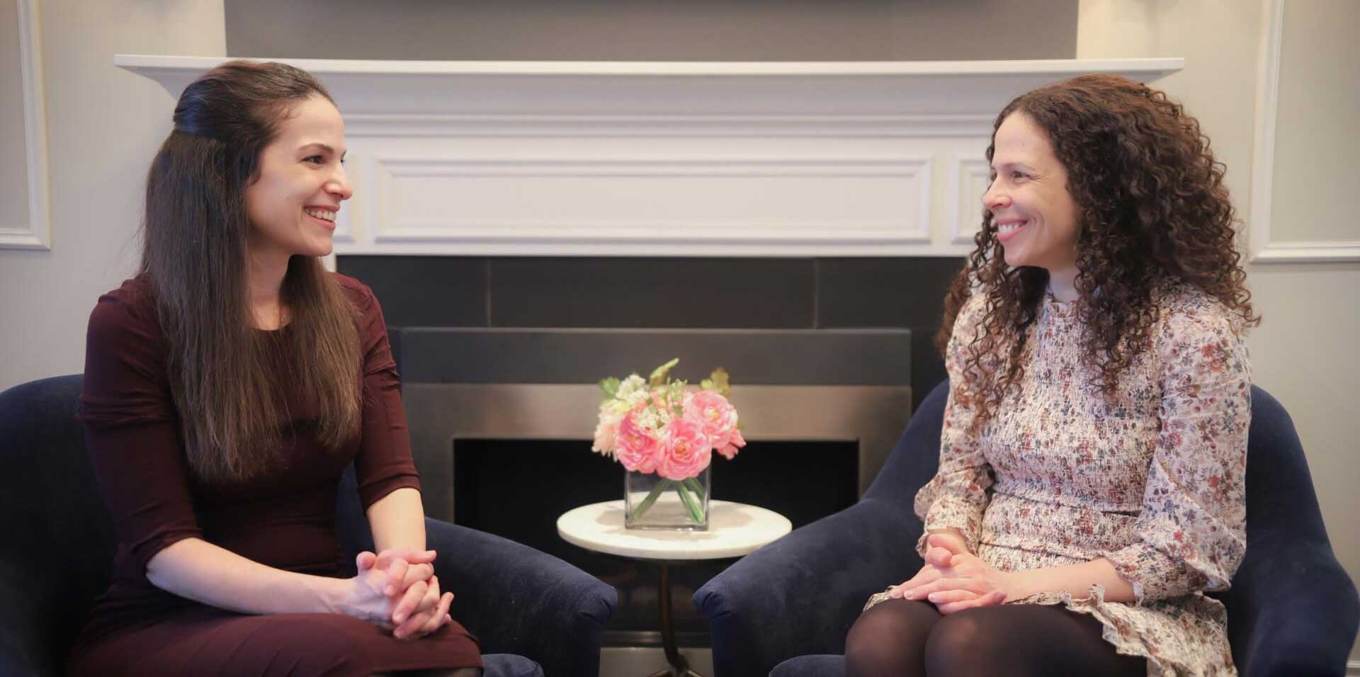 two women sitting in chairs talking to each other